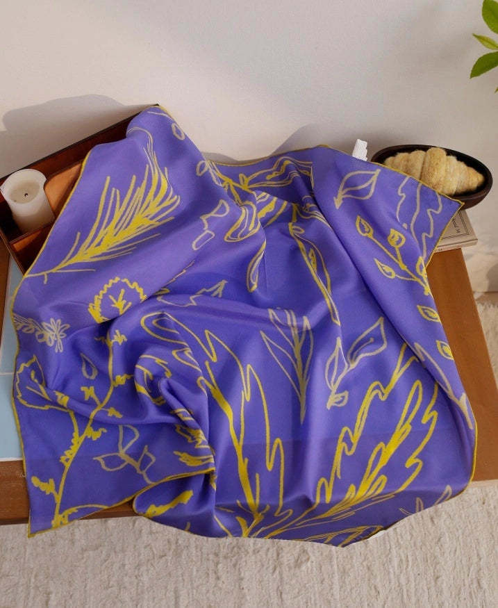 Blue botanical silk square scarf with yellow line art, displayed flat to highlight its elegant design and vibrant colors.