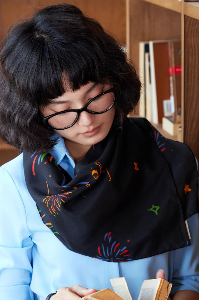 Fireworks Ballerina silk scarf in midnight black, styled as a neck scarf to emphasize its timeless elegance.