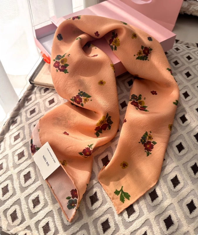Close-up of light orange floral silk scarf, showcasing the intricate floral pattern and luxurious texture.