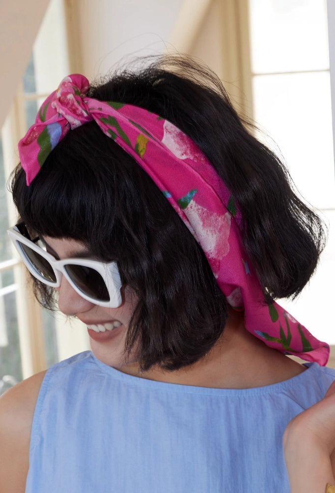 Berry Powder silk square scarf (63x63cm) worn as a headscarf, displaying its pink morning glory pattern on lightweight mulberry silk.